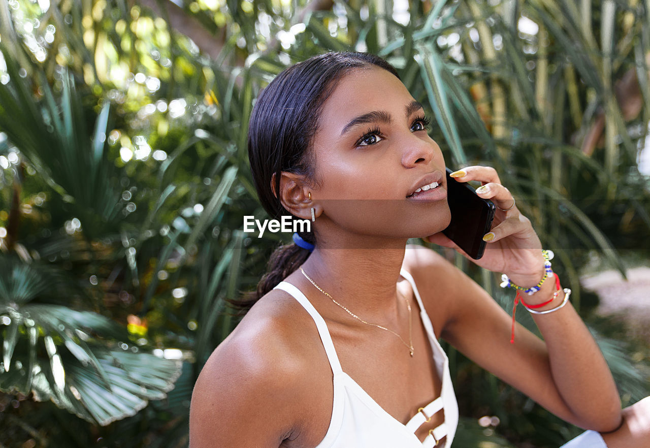 Smiling young woman talking on mobile phone outdoors