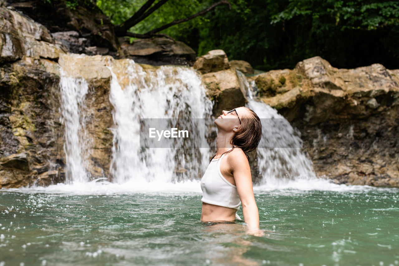 Tropical nature and vacation. woman swimming in the mountain river with a waterfall