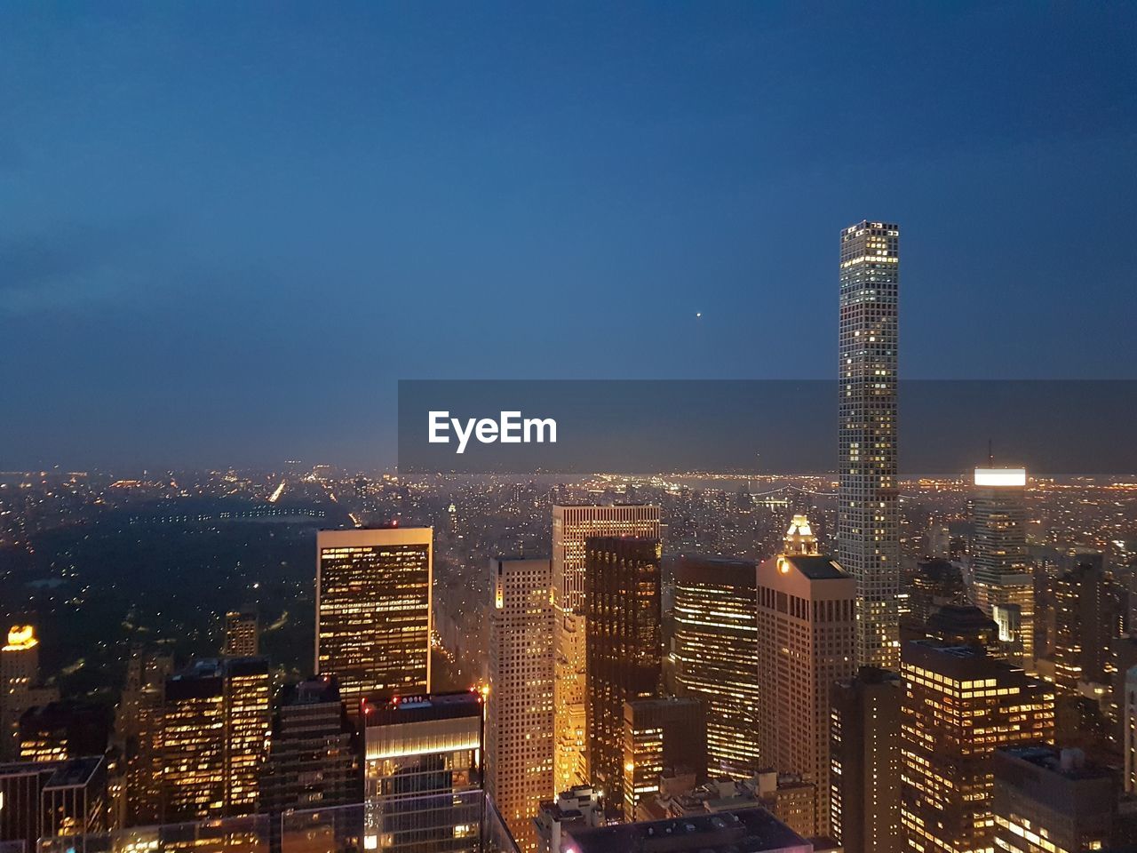 View of illuminated cityscape against blue sky at dusk