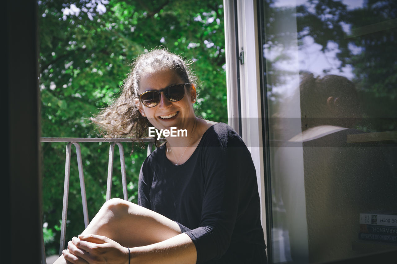 Young woman sitting on window sill