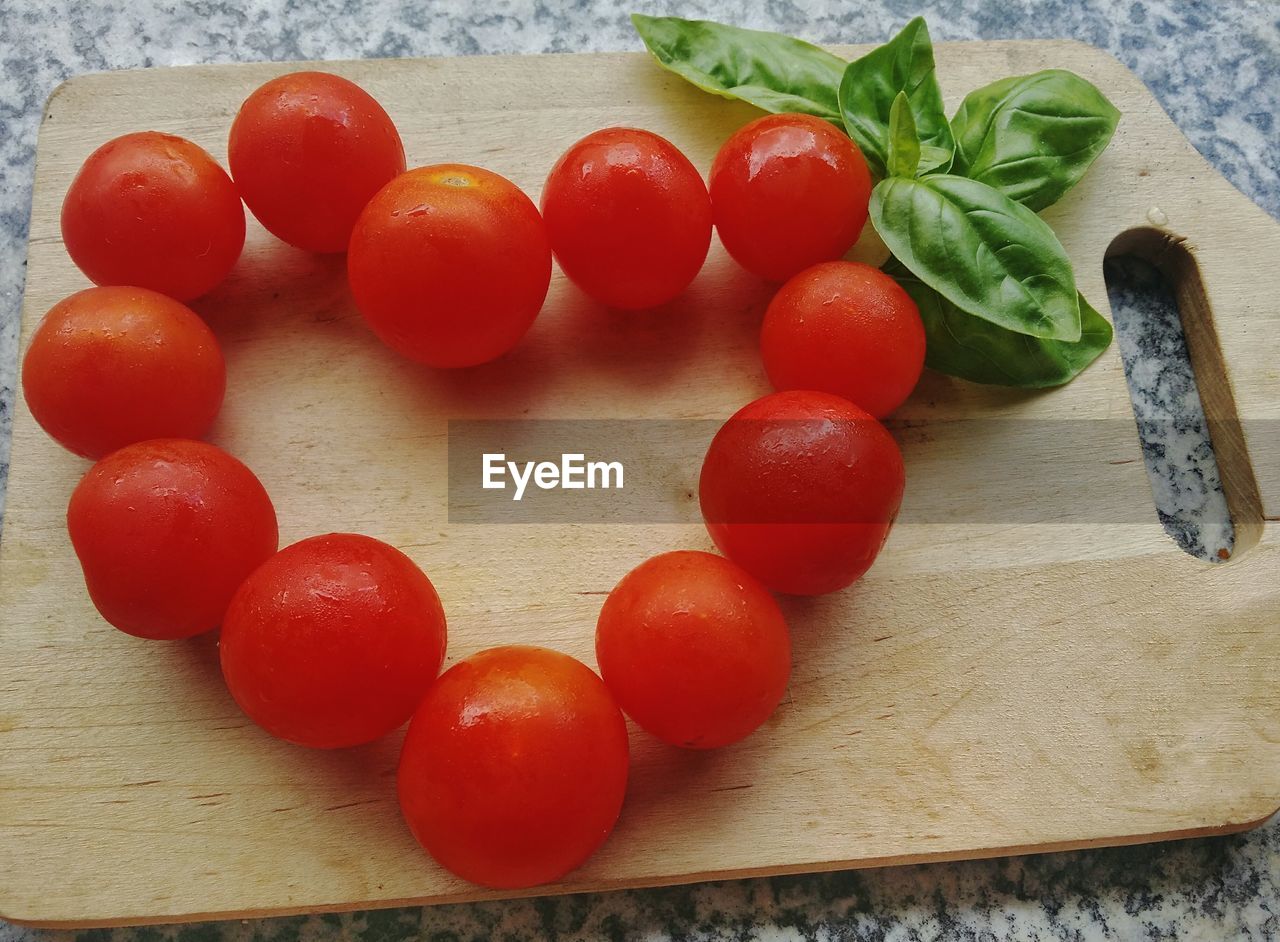 HIGH ANGLE VIEW OF CHERRY TOMATOES ON CUTTING BOARD