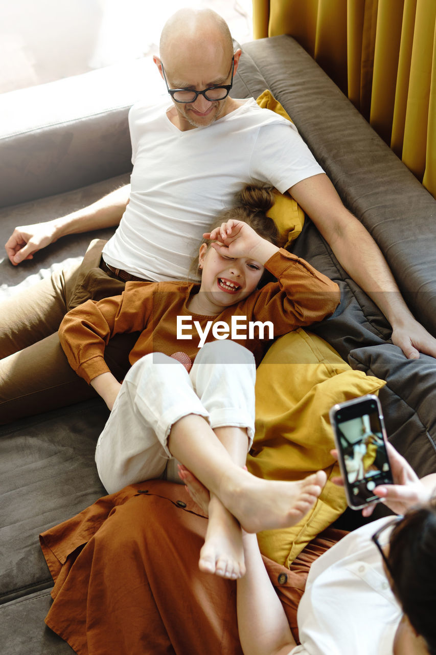 High angle view of father with daughter sitting on sofa