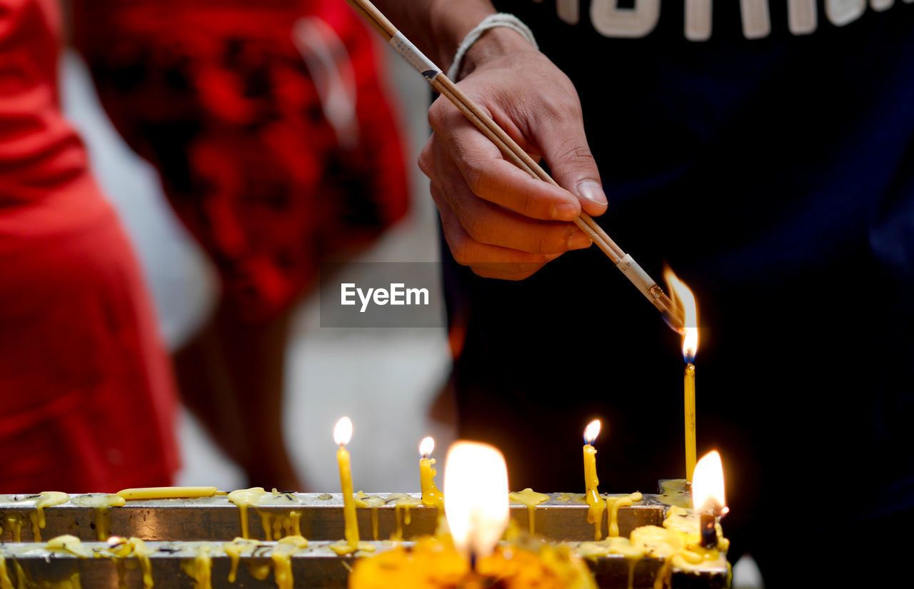 Midsection of man burning incense at temple