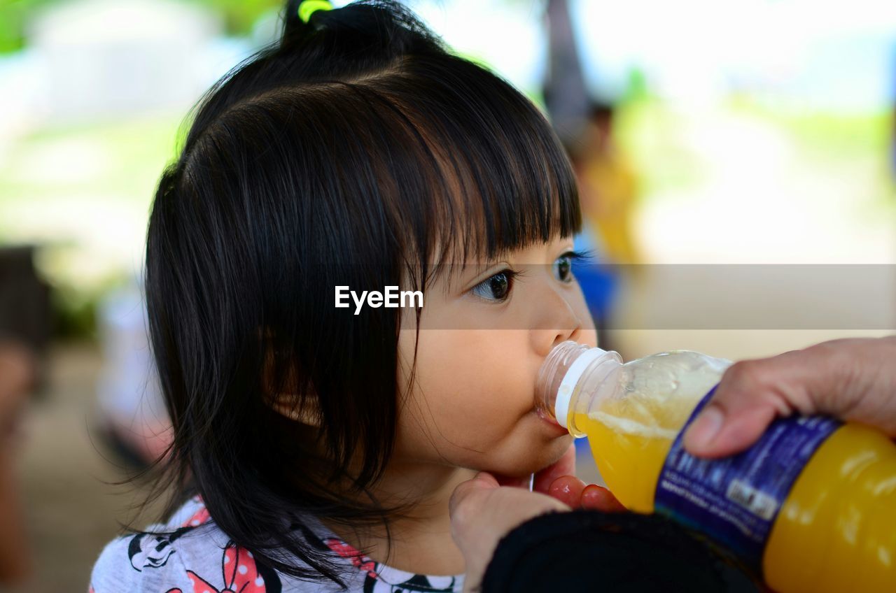 CLOSE-UP PORTRAIT OF A GIRL DRINKING WATER FROM OUTDOORS