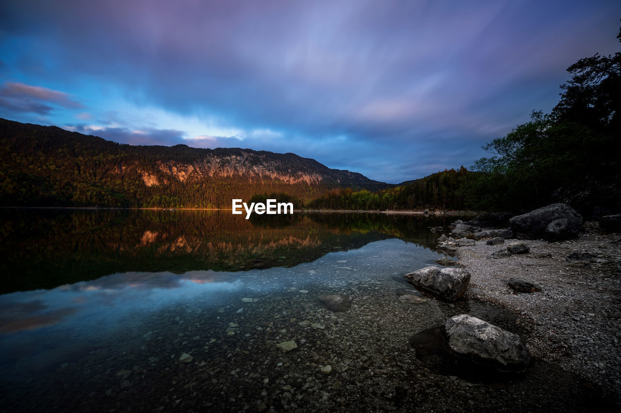 Scenic view of lake by mountains against sky