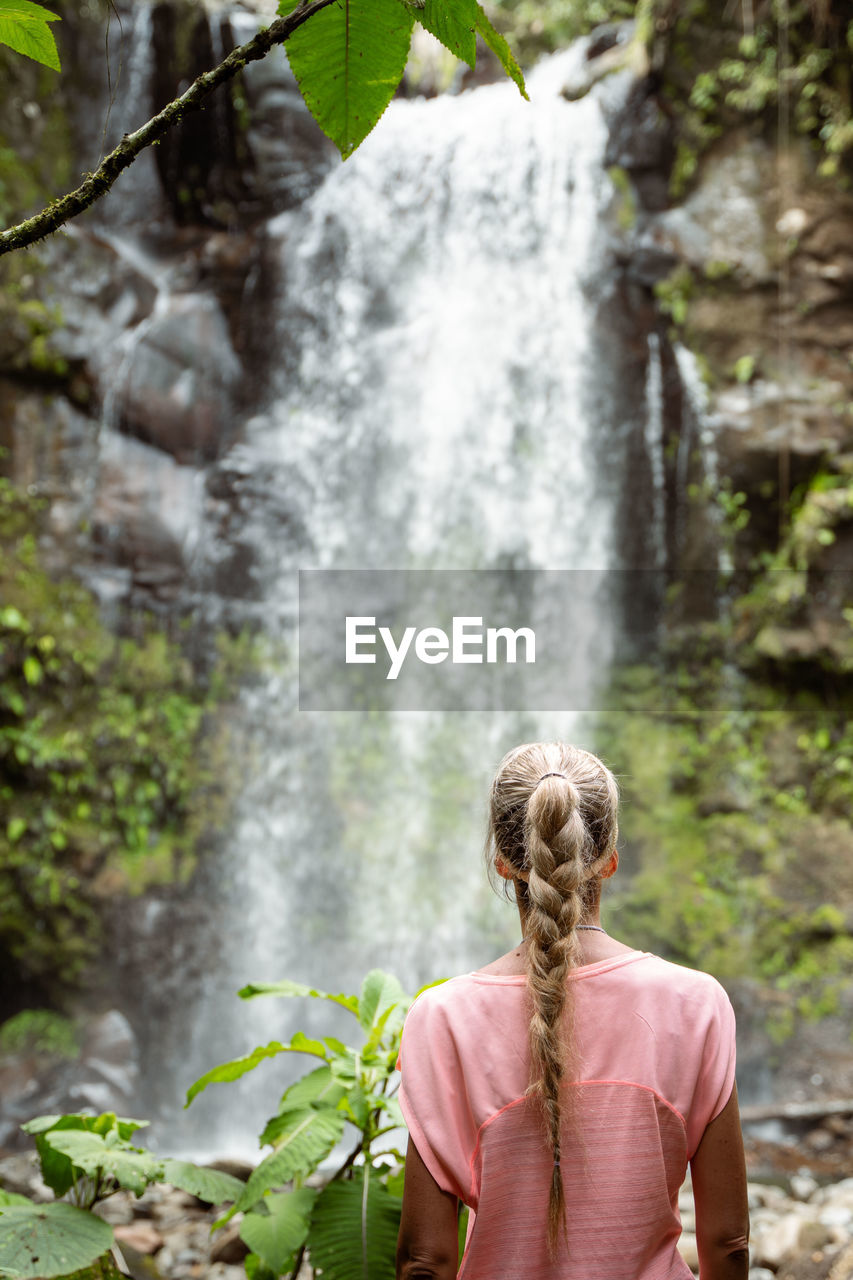 rear view of woman standing by waterfall