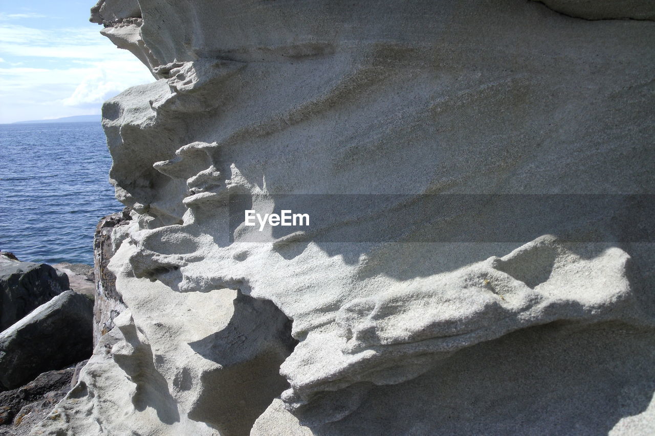 Close-up of rocks in sea against sky