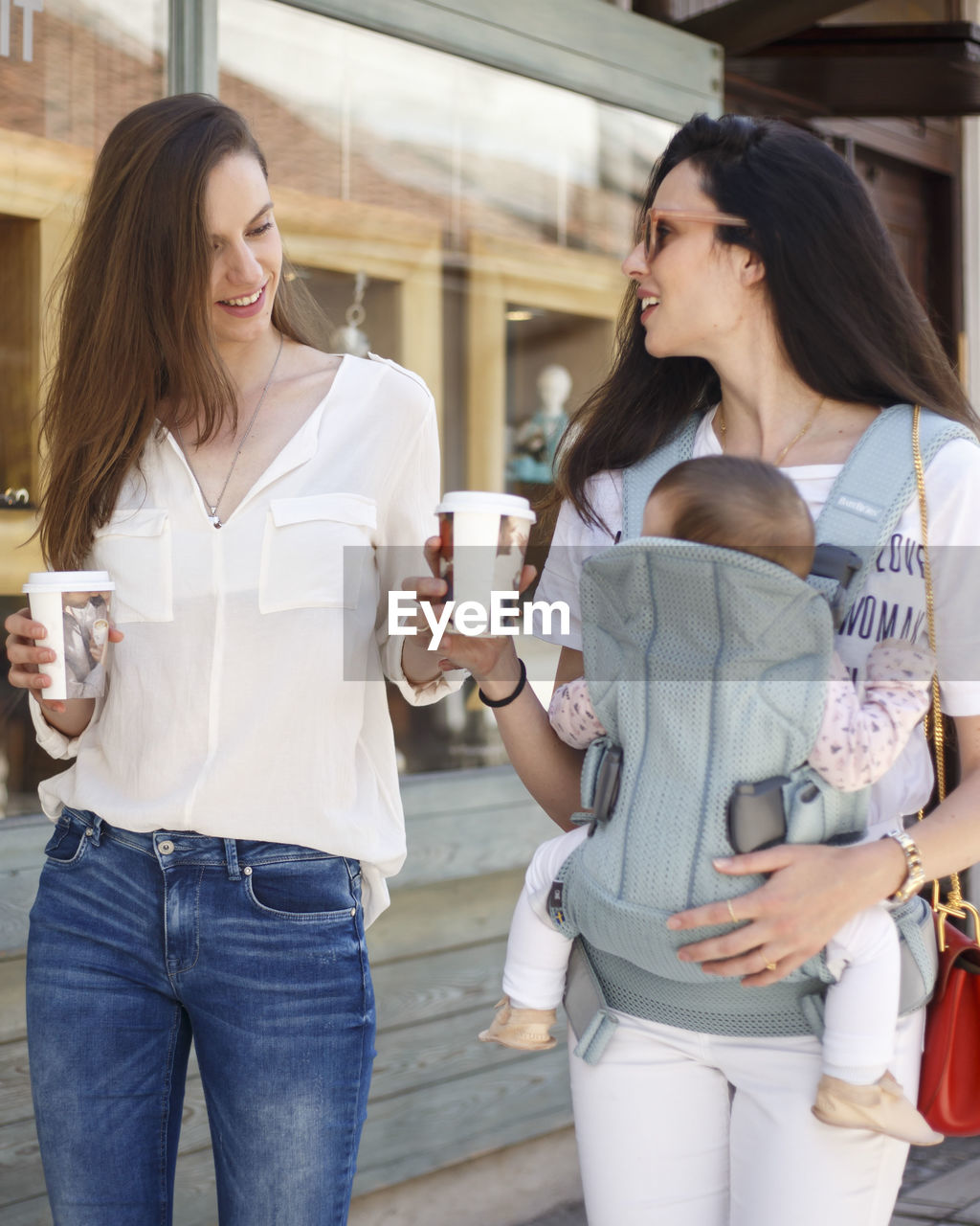 Two young women walking with baby in carrier 