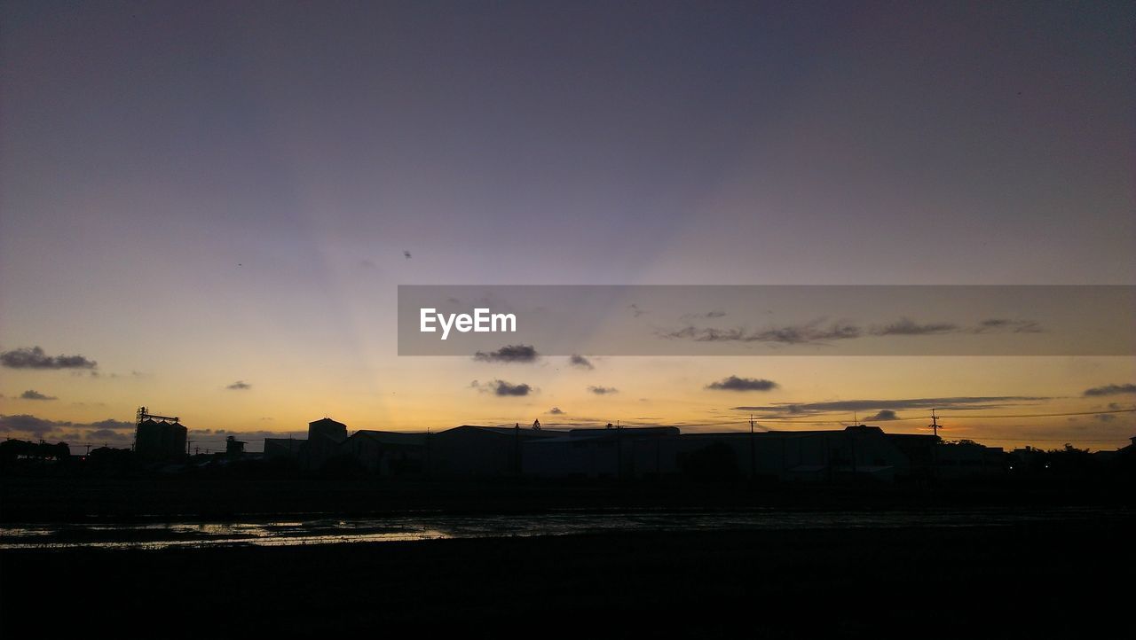 Silhouette city against sky at sunset