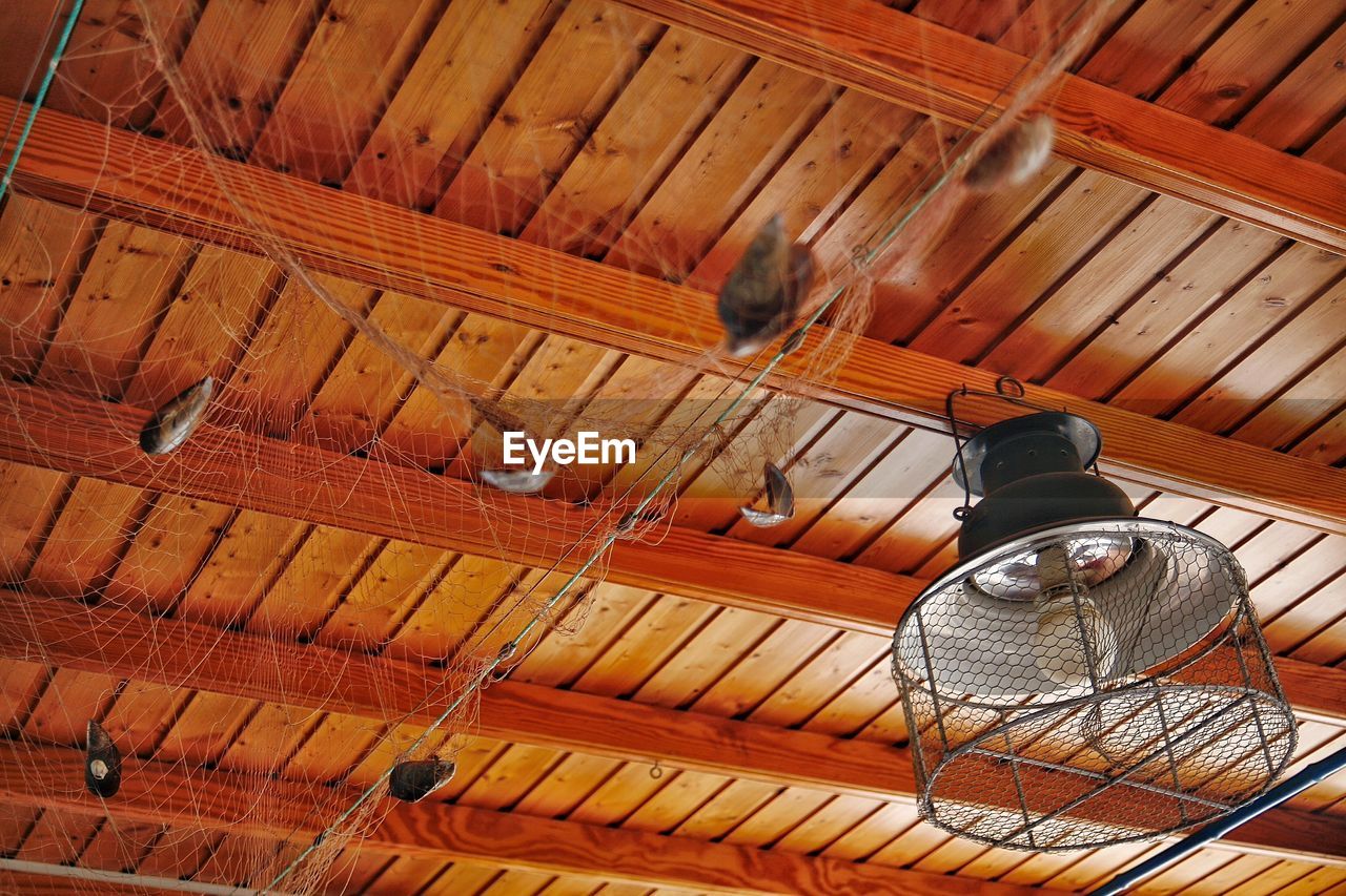 Low angle view of pendant light hanging from wooden ceiling