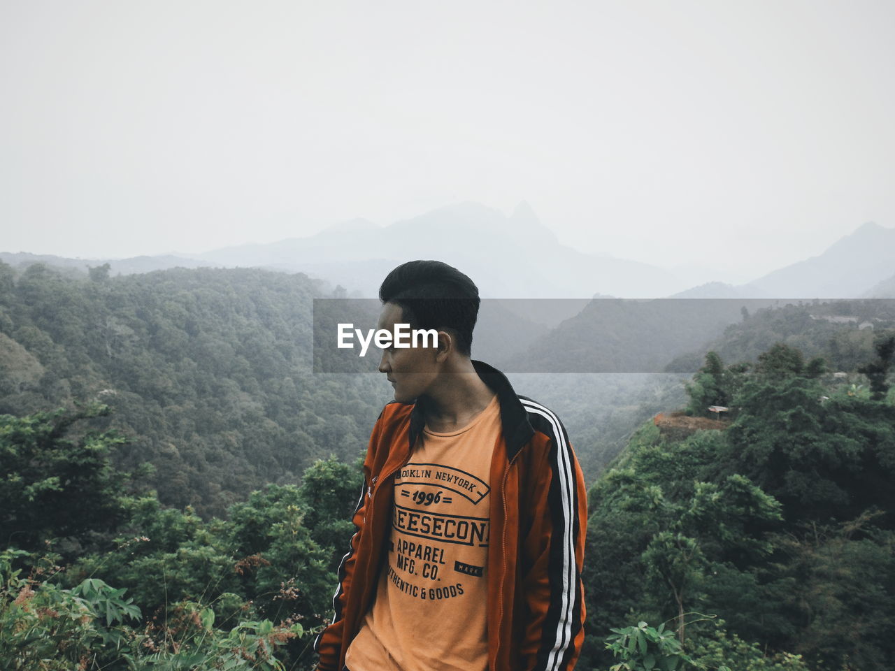 MAN LOOKING AT MOUNTAIN RANGE AGAINST SKY