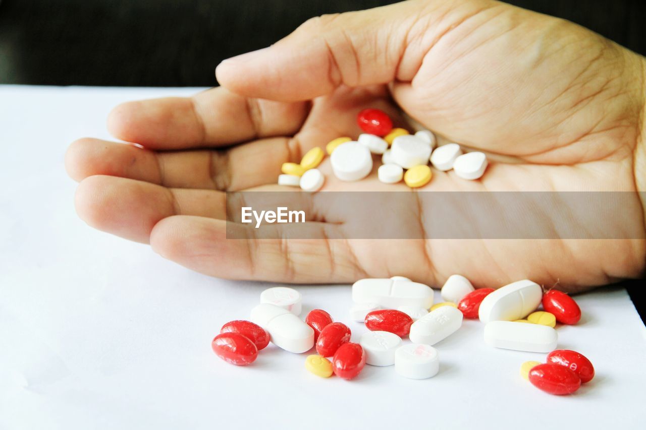 Cropped image of hand holding capsules on table