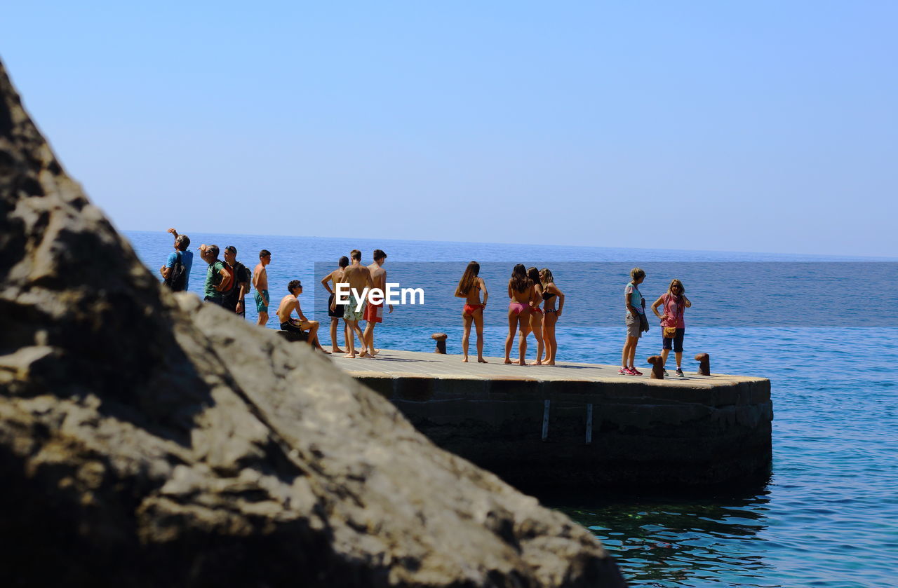 PEOPLE AT SEASIDE AGAINST CLEAR SKY