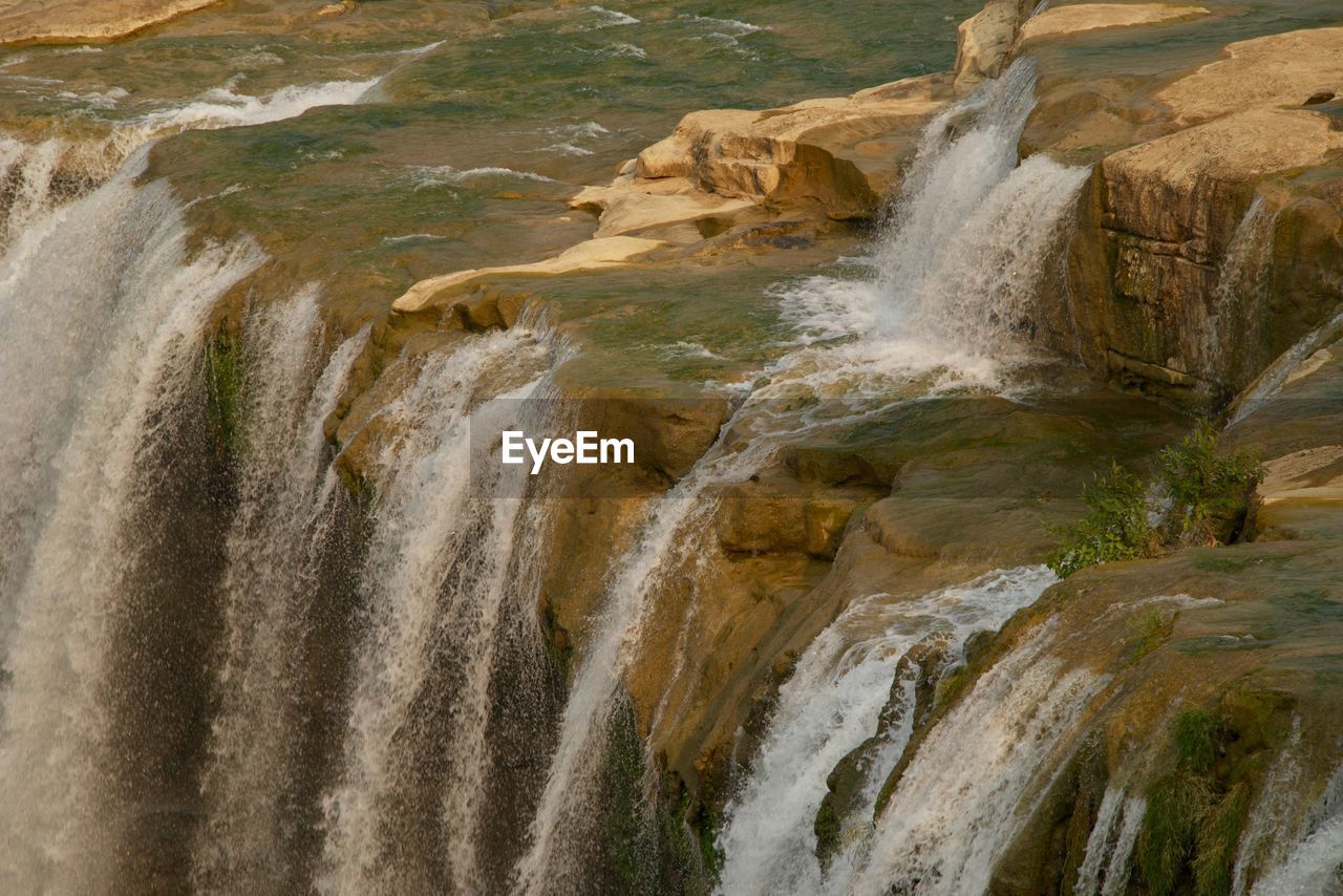 SCENIC VIEW OF WATERFALL AGAINST RIVER