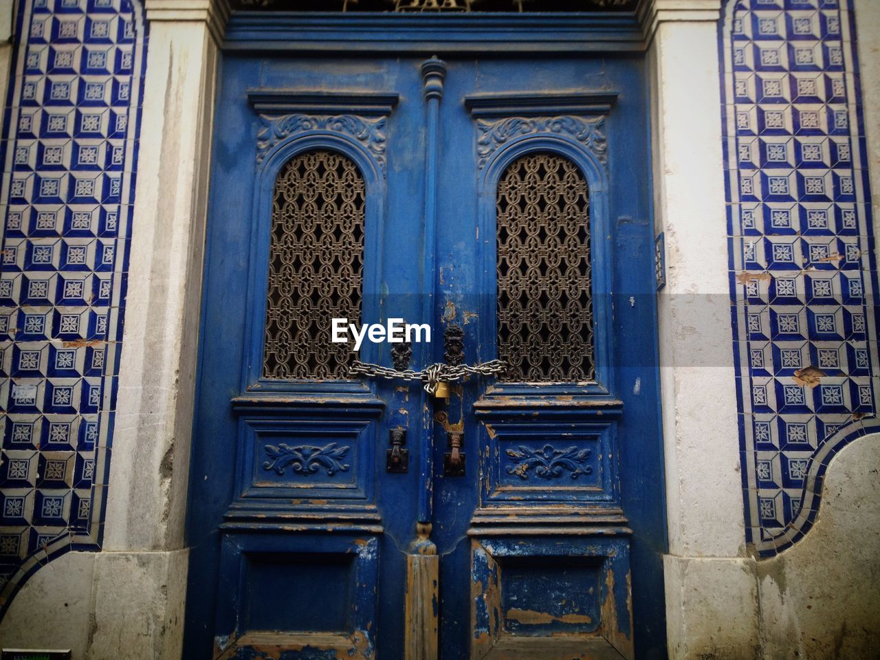 Closed old blue door locked with chain