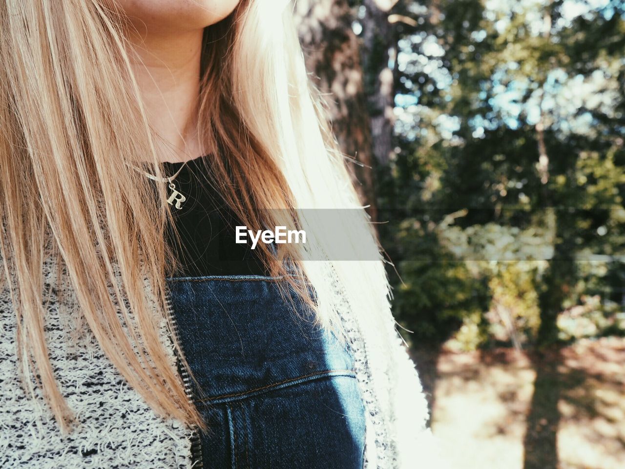 Midsection of young woman standing against tree