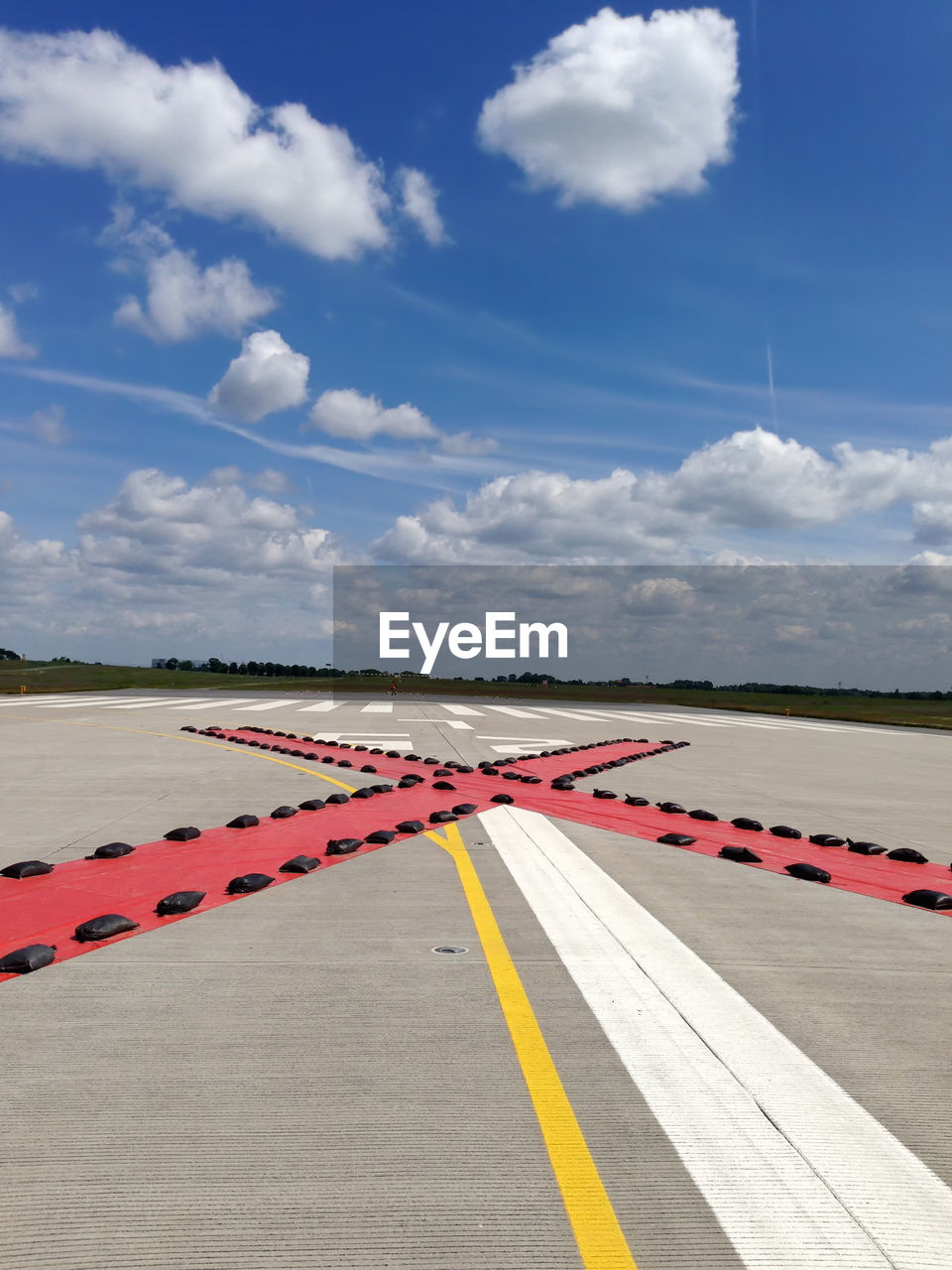 Cross shape on airport runway against sky