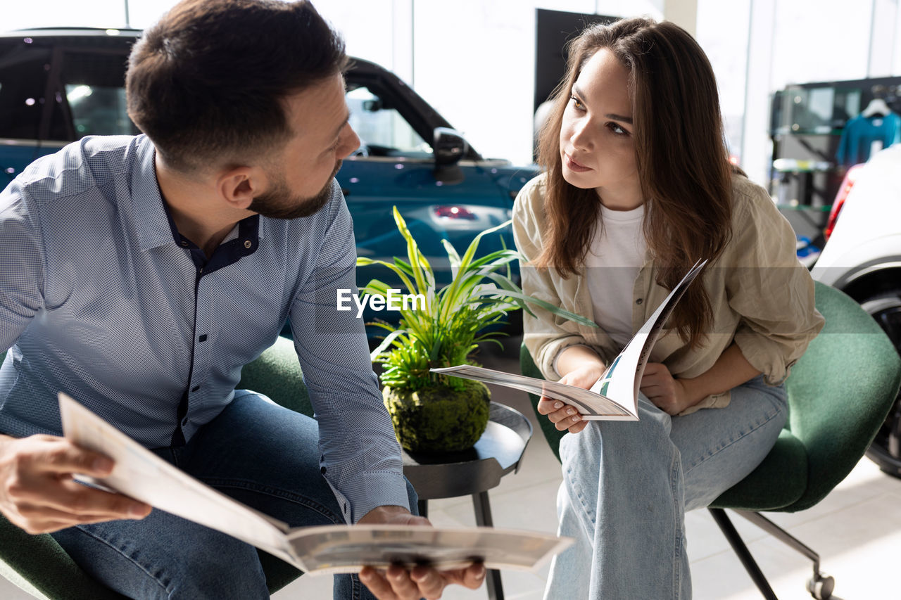 Salesman and customer discussing at car showroom