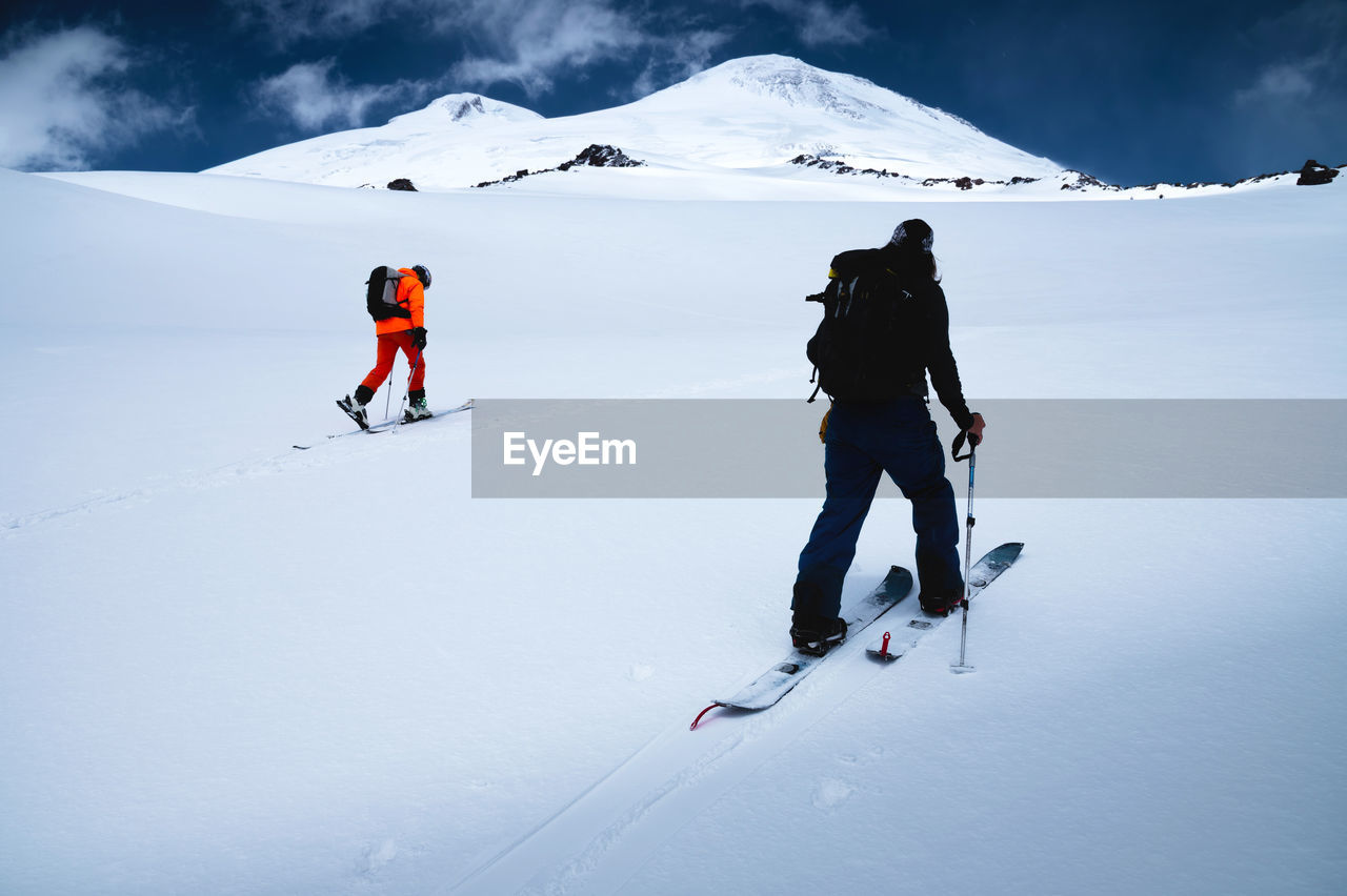 Two freeride skiers climb up the fresh snow in a ski tour. the summit of mount elbrus 