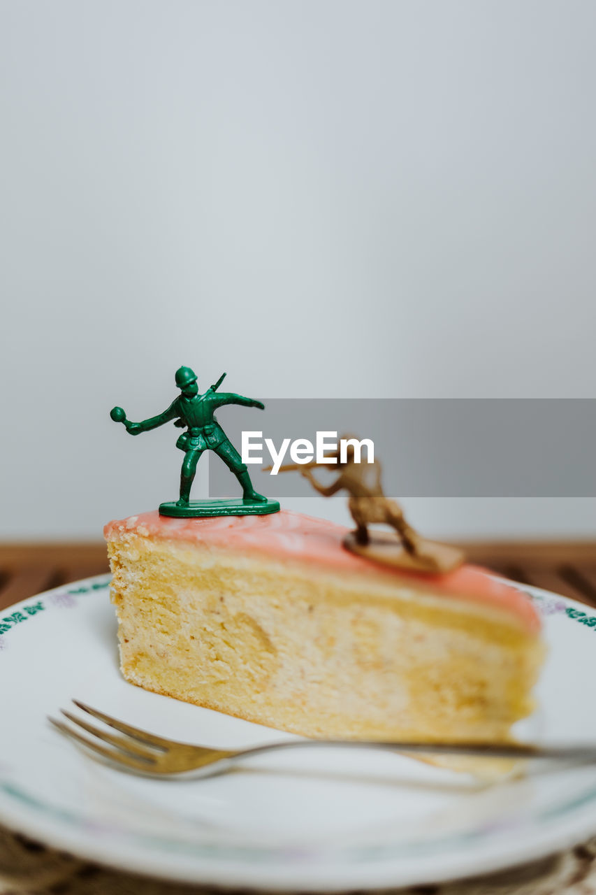 Two toy soldiers fighting on the top of a piece of cake about calories - close up white background