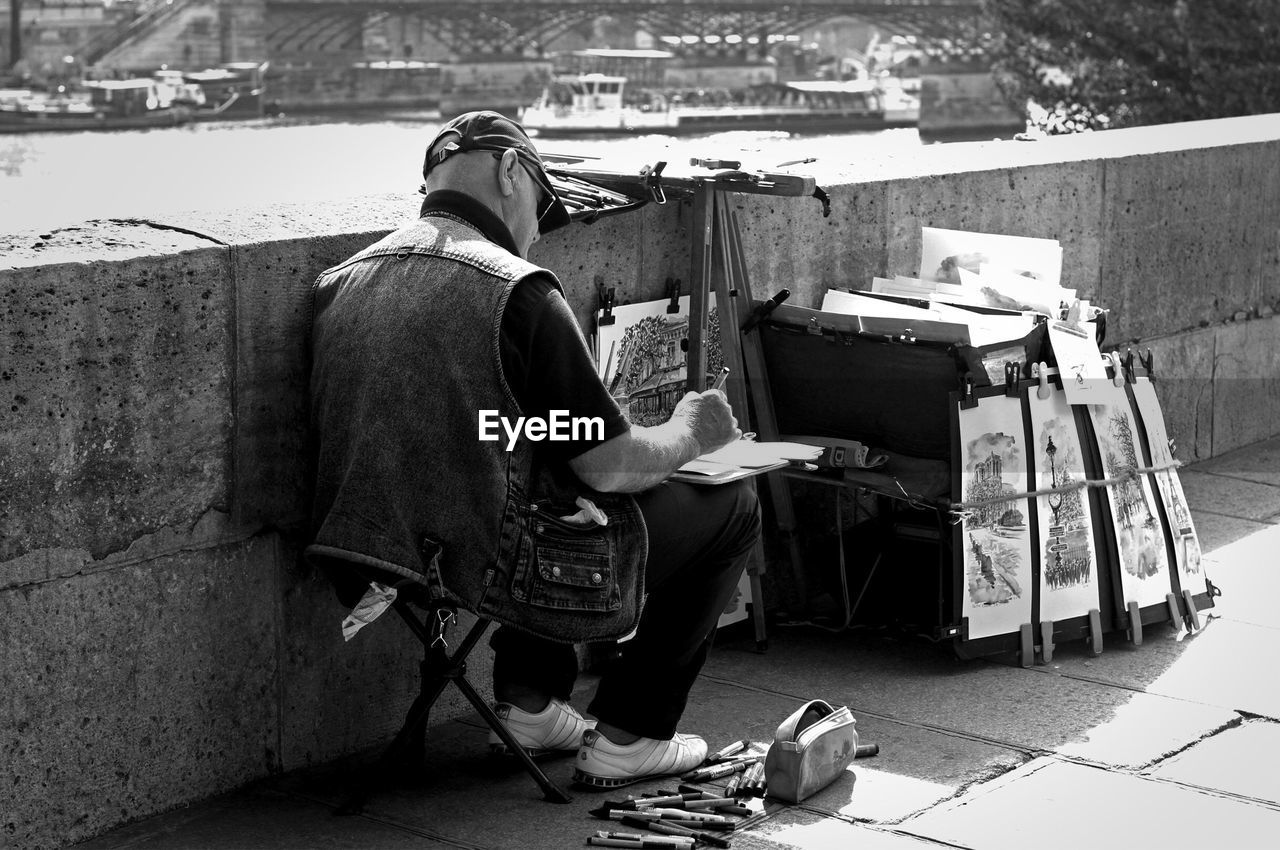 REAR VIEW OF MAN WORKING ON BOOK WITH CITY