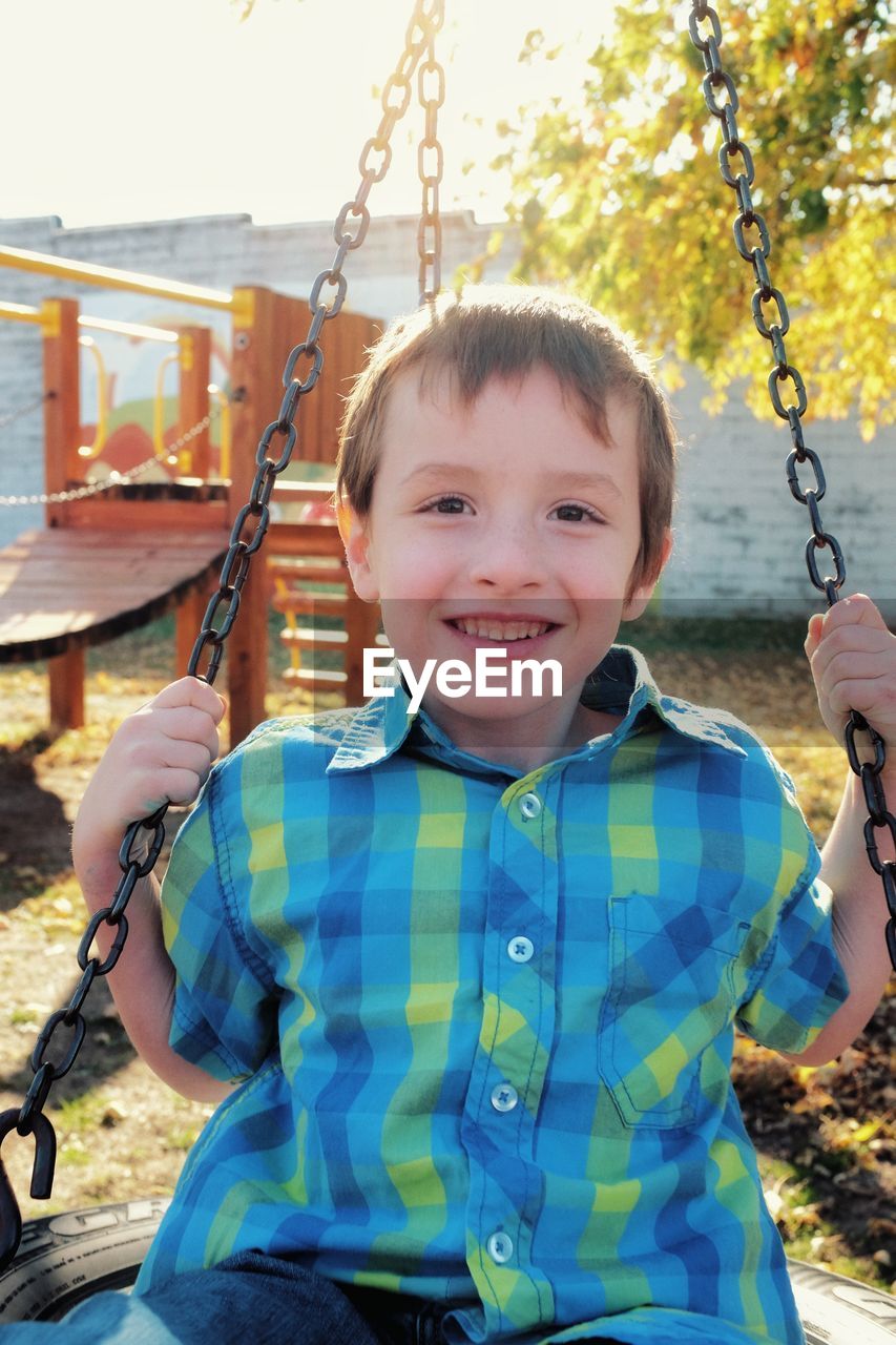 Portrait of smiling boy sitting on swing