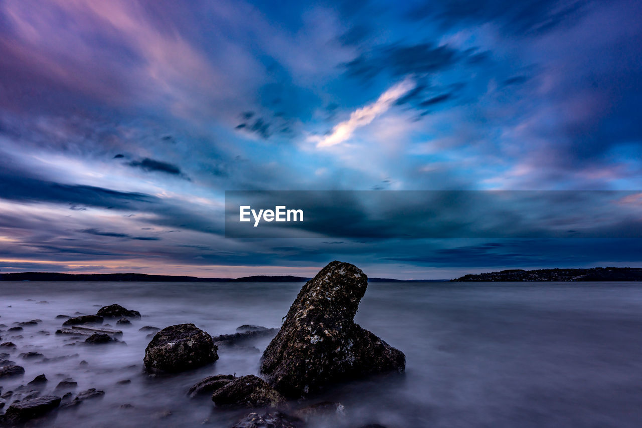 ROCKS IN SEA AGAINST SUNSET SKY