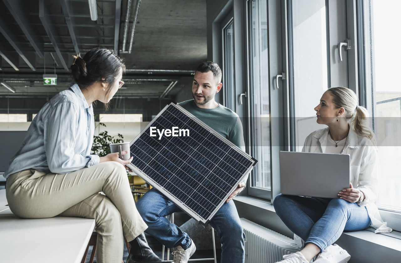 Multiracial business colleagues discussing over solar panel in meeting at office