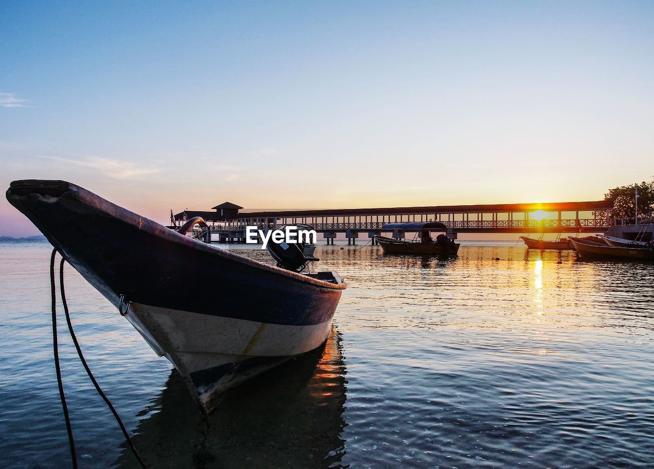 Boats in river at sunset