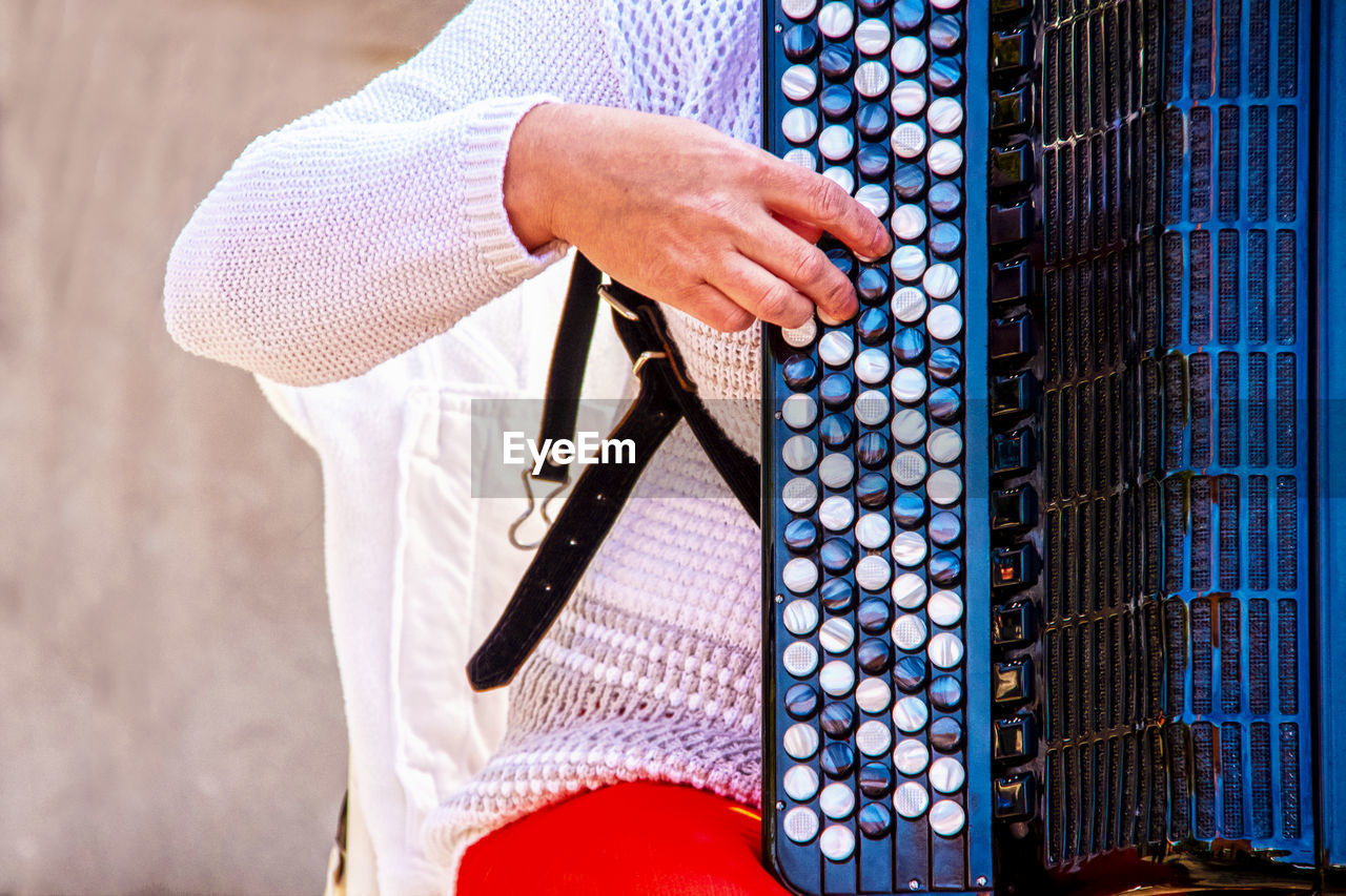 Midsection of man playing musical instrument outdoors