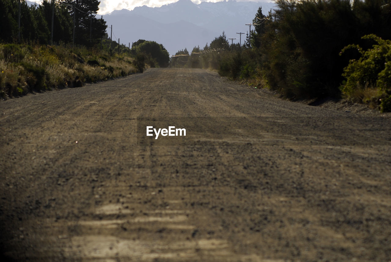 road, tree, plant, landscape, environment, sky, nature, land, soil, transportation, the way forward, mountain, scenics - nature, dirt, no people, dirt road, infrastructure, beauty in nature, rural area, tranquility, travel, field, outdoors, natural environment, cloud, diminishing perspective, non-urban scene, forest, tranquil scene, rural scene, travel destinations, mountain range, vanishing point