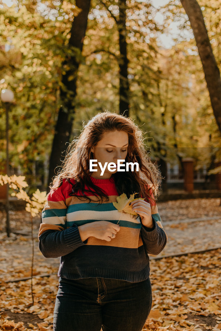 BEAUTIFUL YOUNG WOMAN STANDING IN AUTUMN