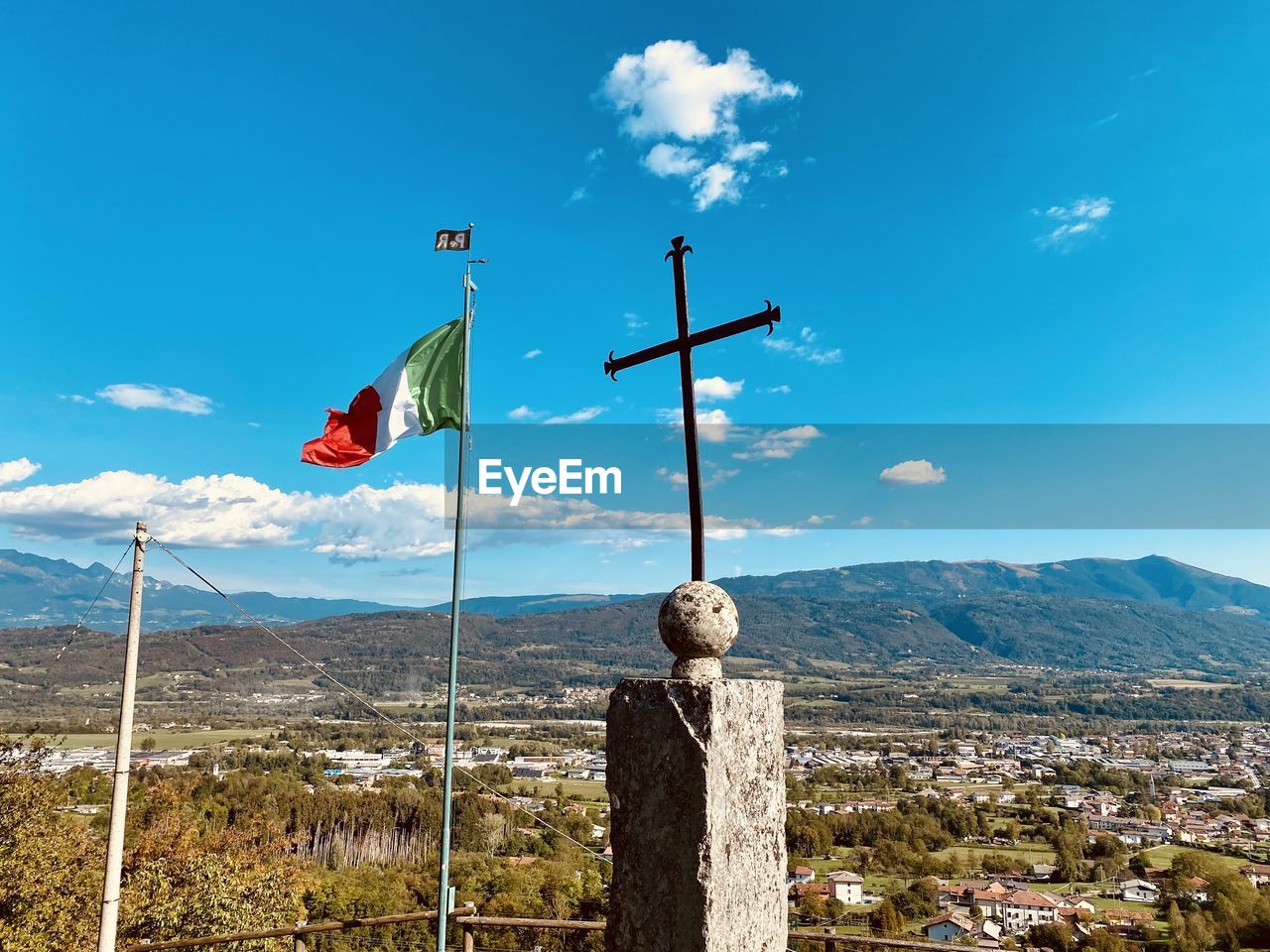 sky, mountain, flag, nature, environment, landscape, cloud, scenics - nature, no people, blue, mountain range, day, beauty in nature, pole, patriotism, wind, architecture, outdoors, land, tranquility, travel destinations, tranquil scene, cross, built structure, sunlight, travel, sunny, tree