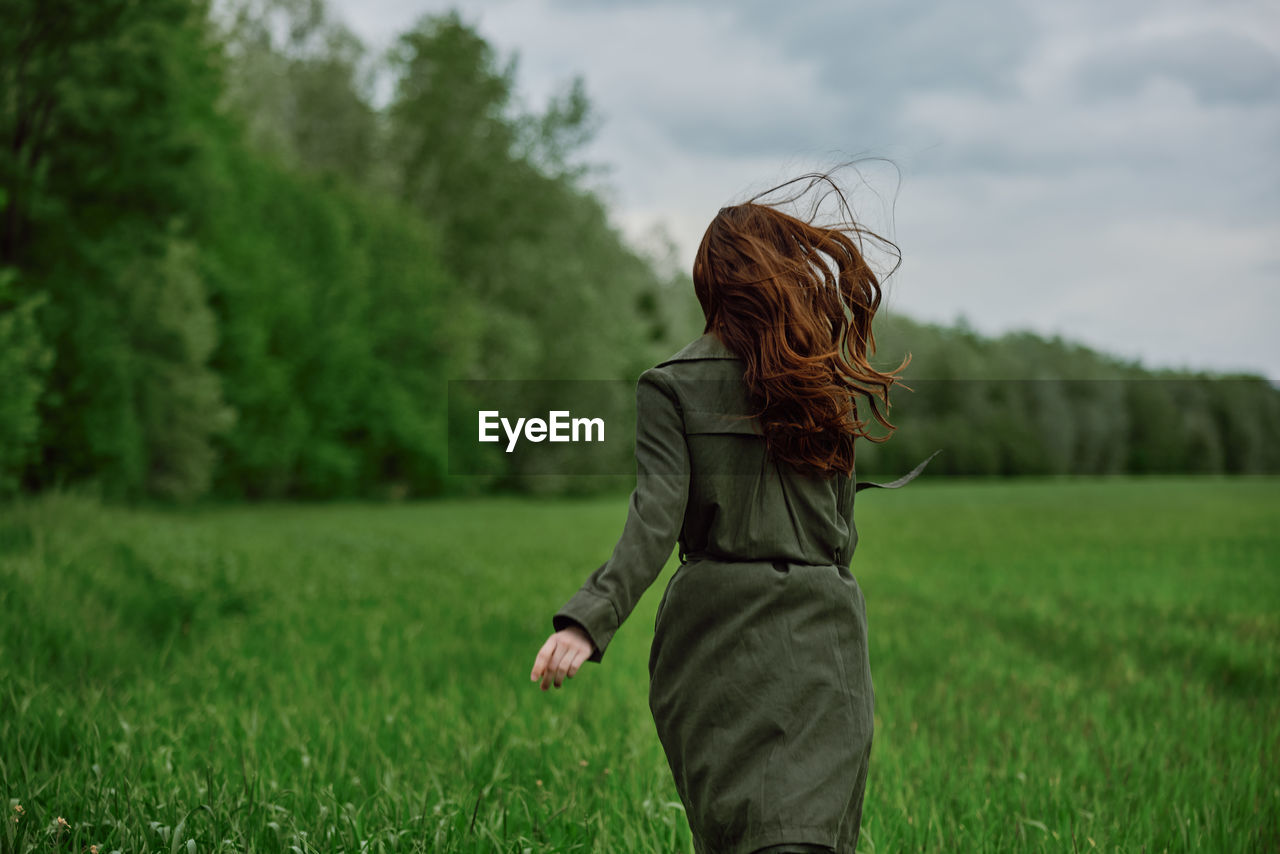 Rear view of young woman running in field