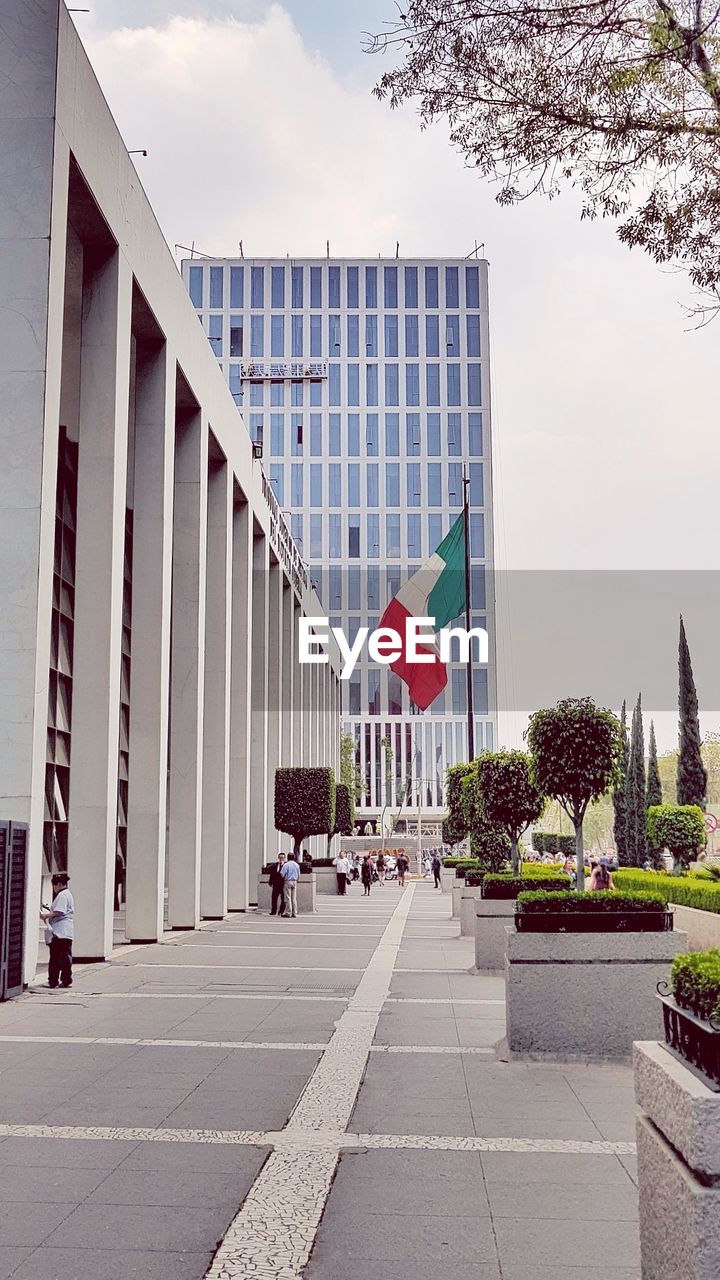 FLAG ON FOOTPATH AMIDST BUILDINGS AGAINST SKY