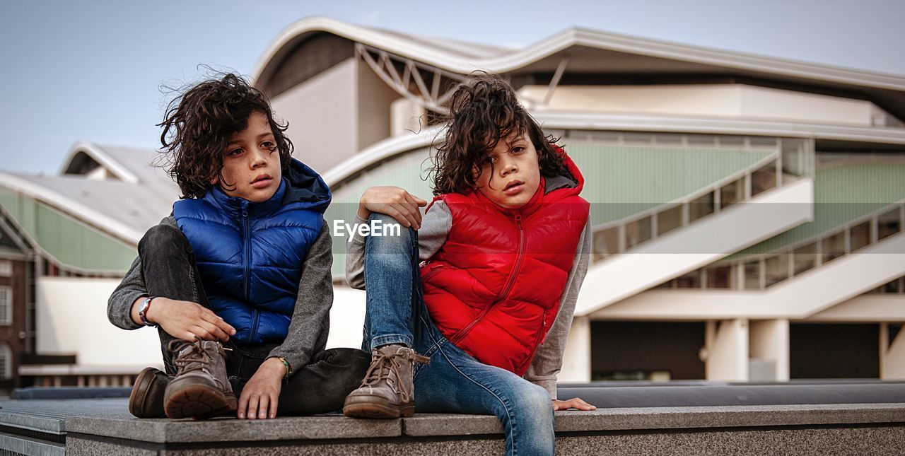 Full length of boys sitting on built structure