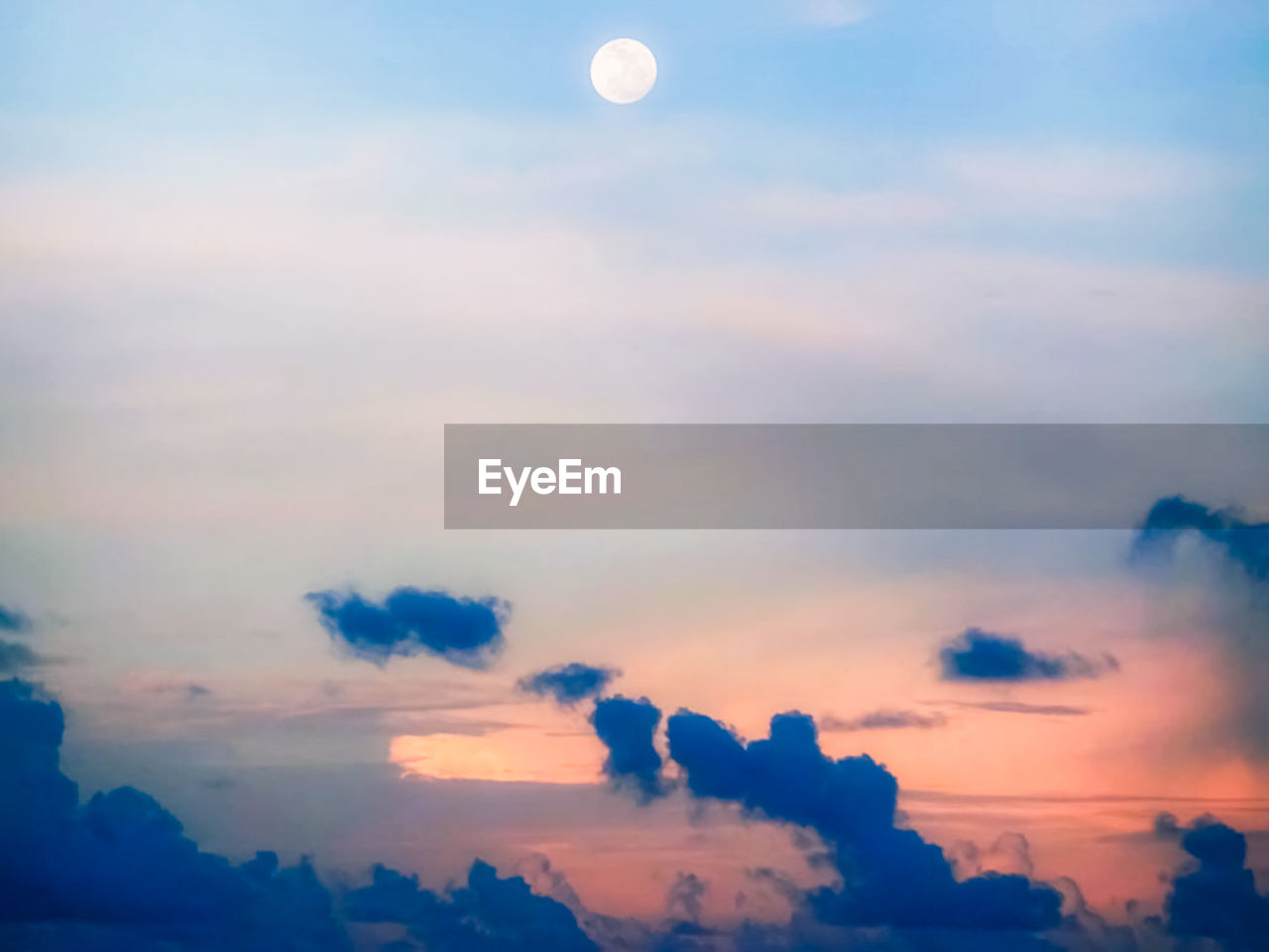 Low angle view of moon in sky at sunset