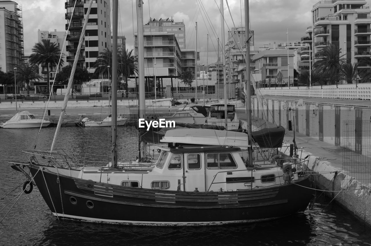 Boats moored in harbor on lake against buildings