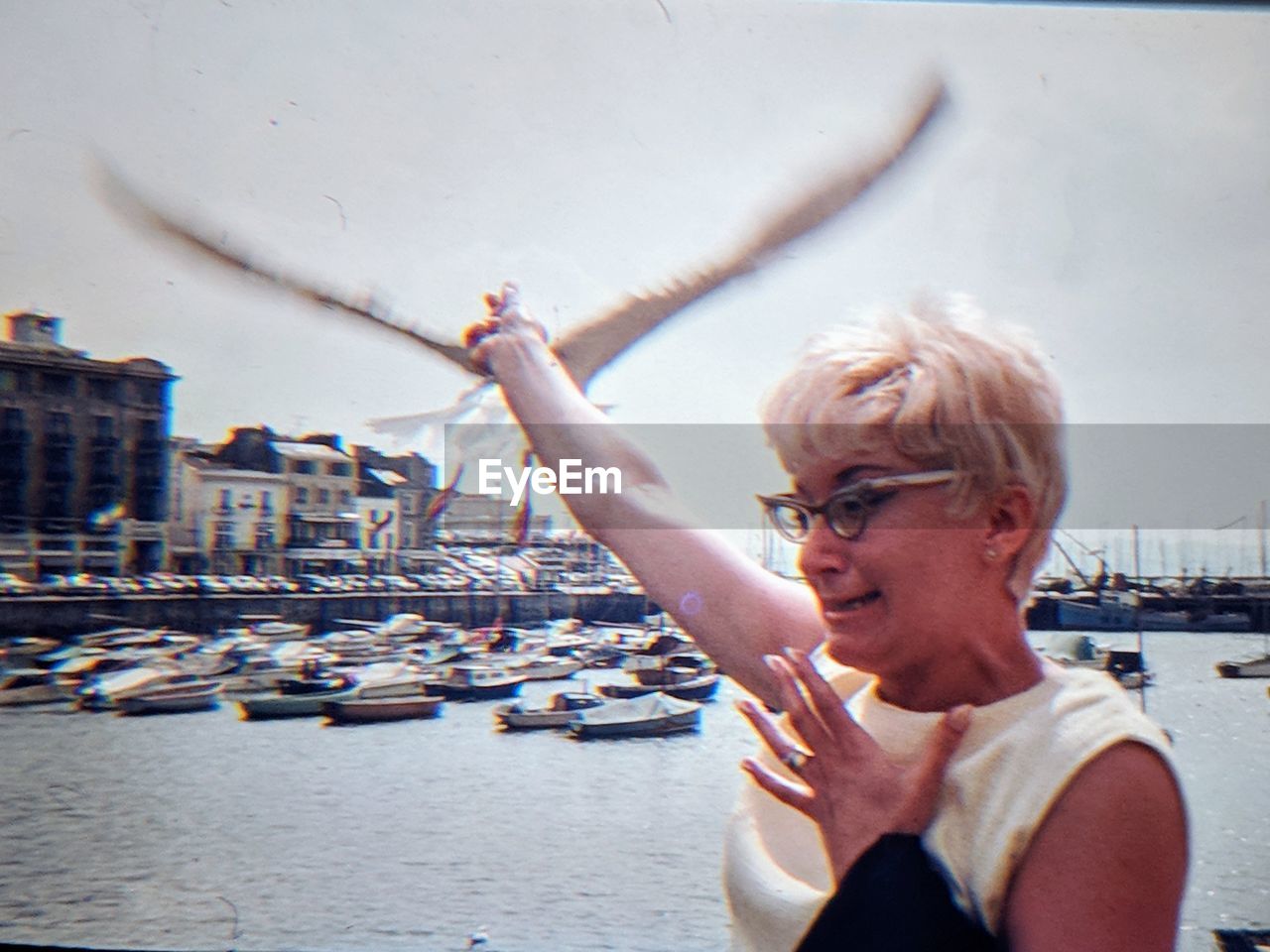 PORTRAIT OF WOMAN WITH ARMS RAISED IN PARK