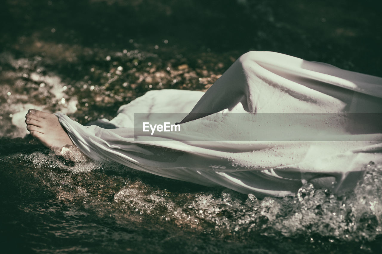 Low section of person lying in stream
