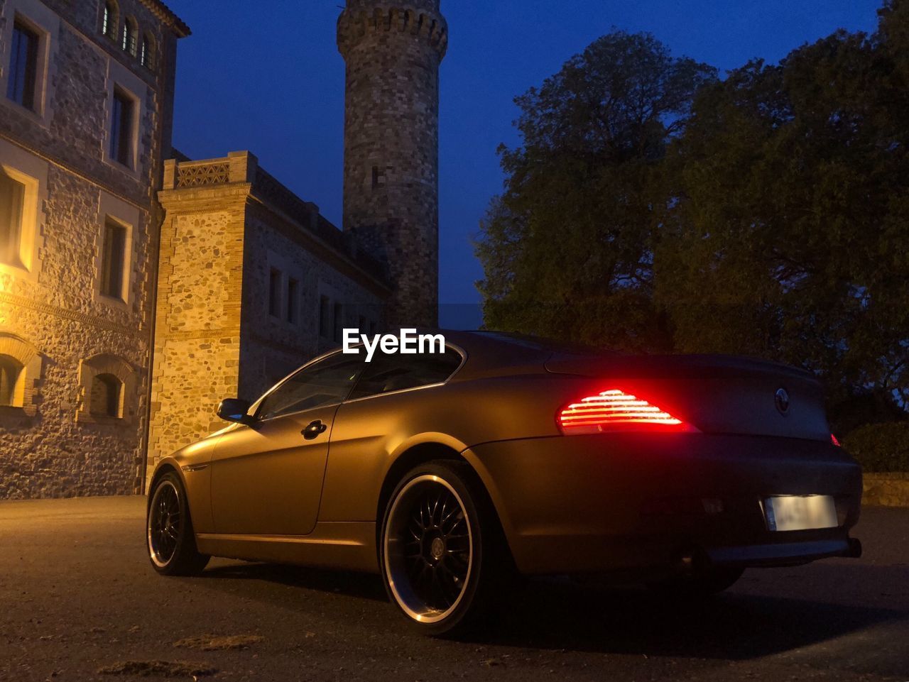 CAR ON STREET AGAINST BUILDINGS AT NIGHT