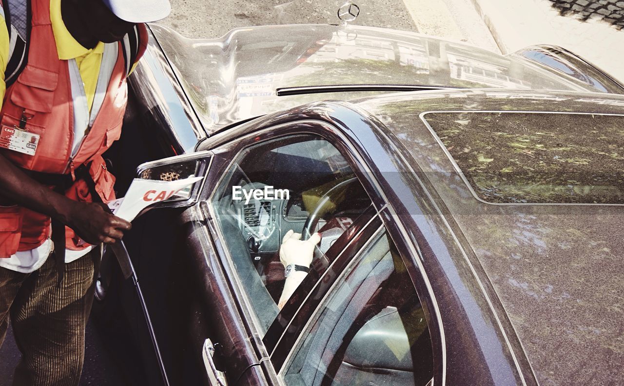 Midsection of worker holding paper by car