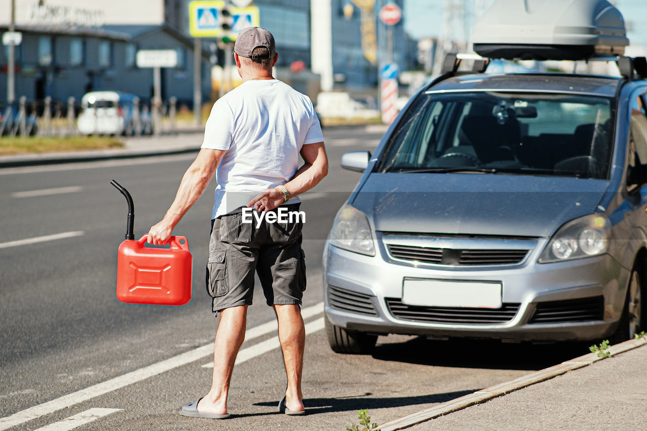 FULL LENGTH REAR VIEW OF MAN STANDING ON STREET