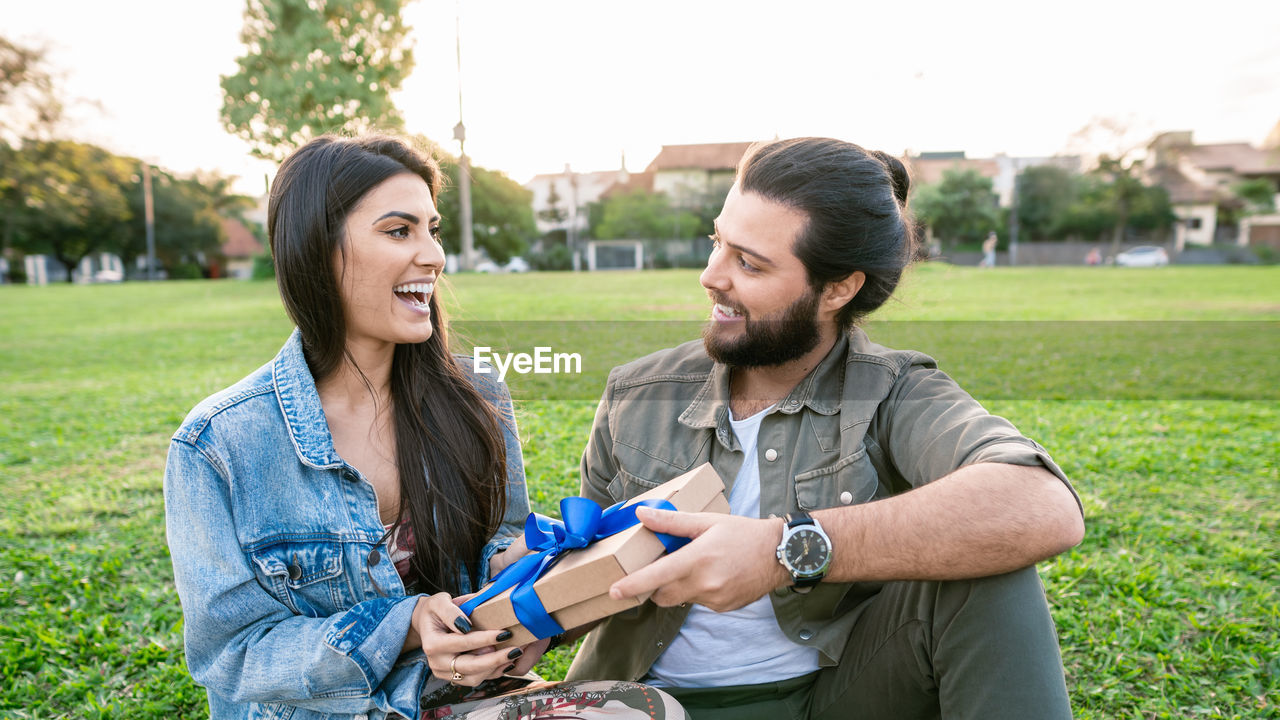 portrait of smiling friends standing against trees at park