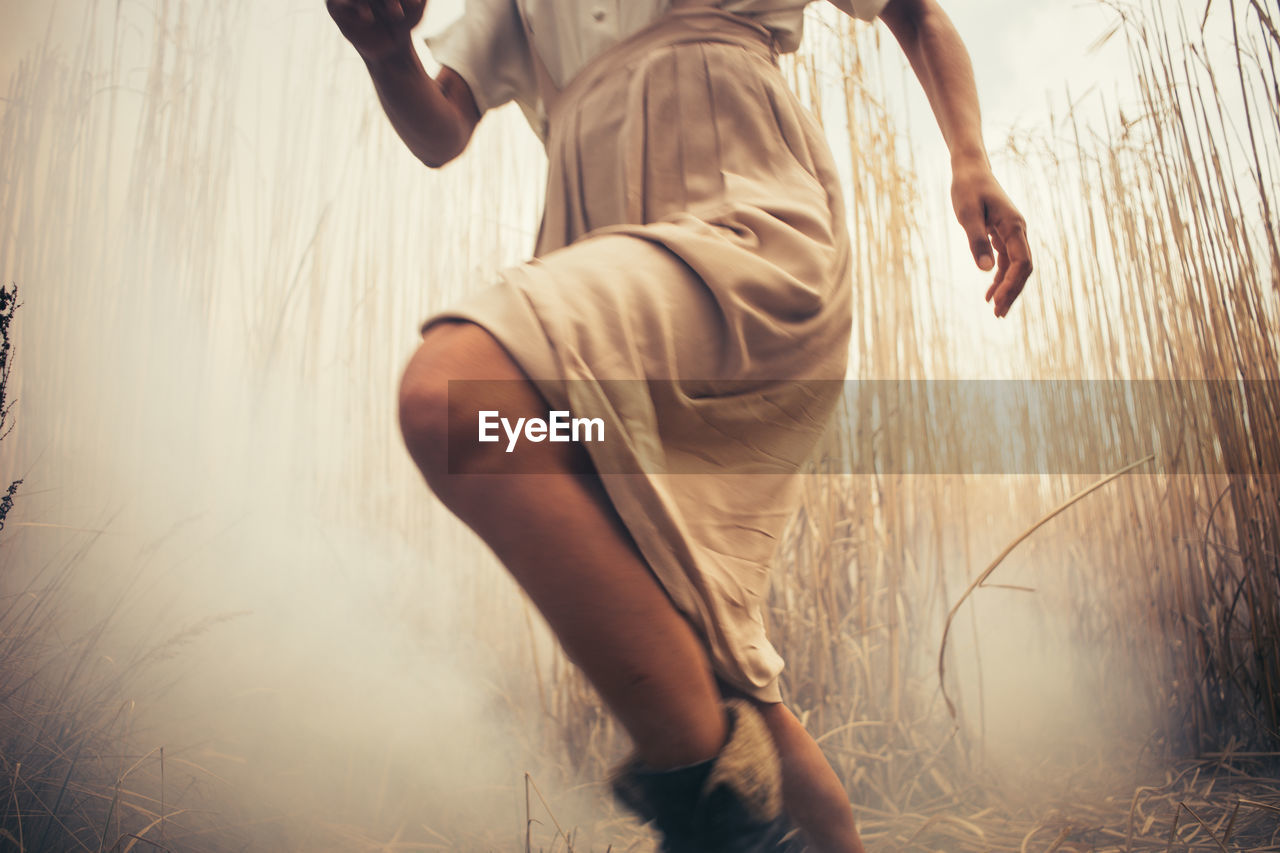 Low section of woman running amidst plants