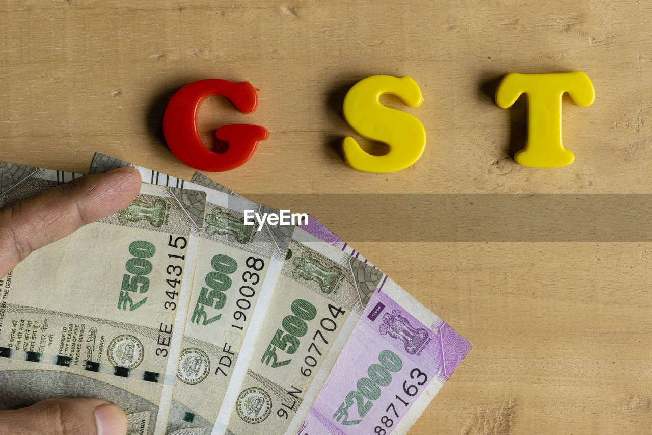 CLOSE-UP OF HUMAN HAND HOLDING TEXT ON YELLOW WALL