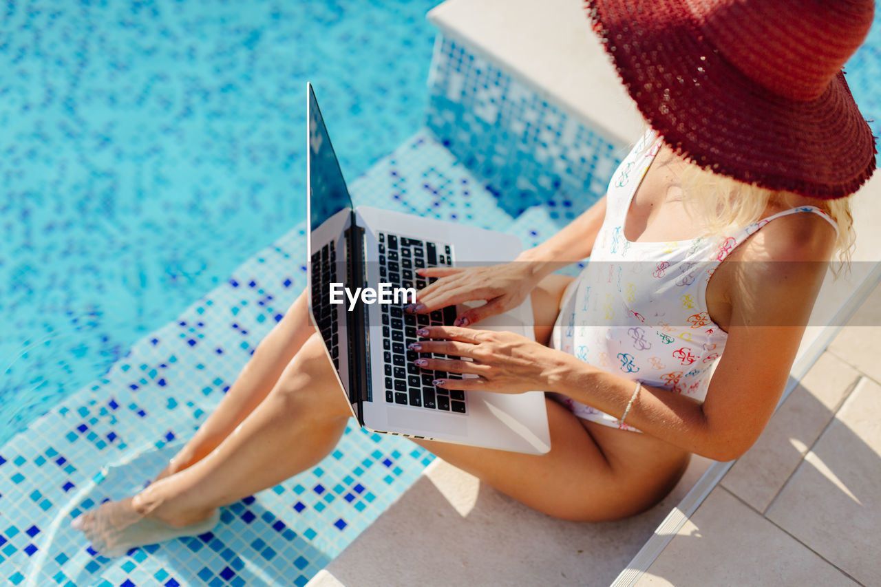 High angle view of woman using hat by swimming pool