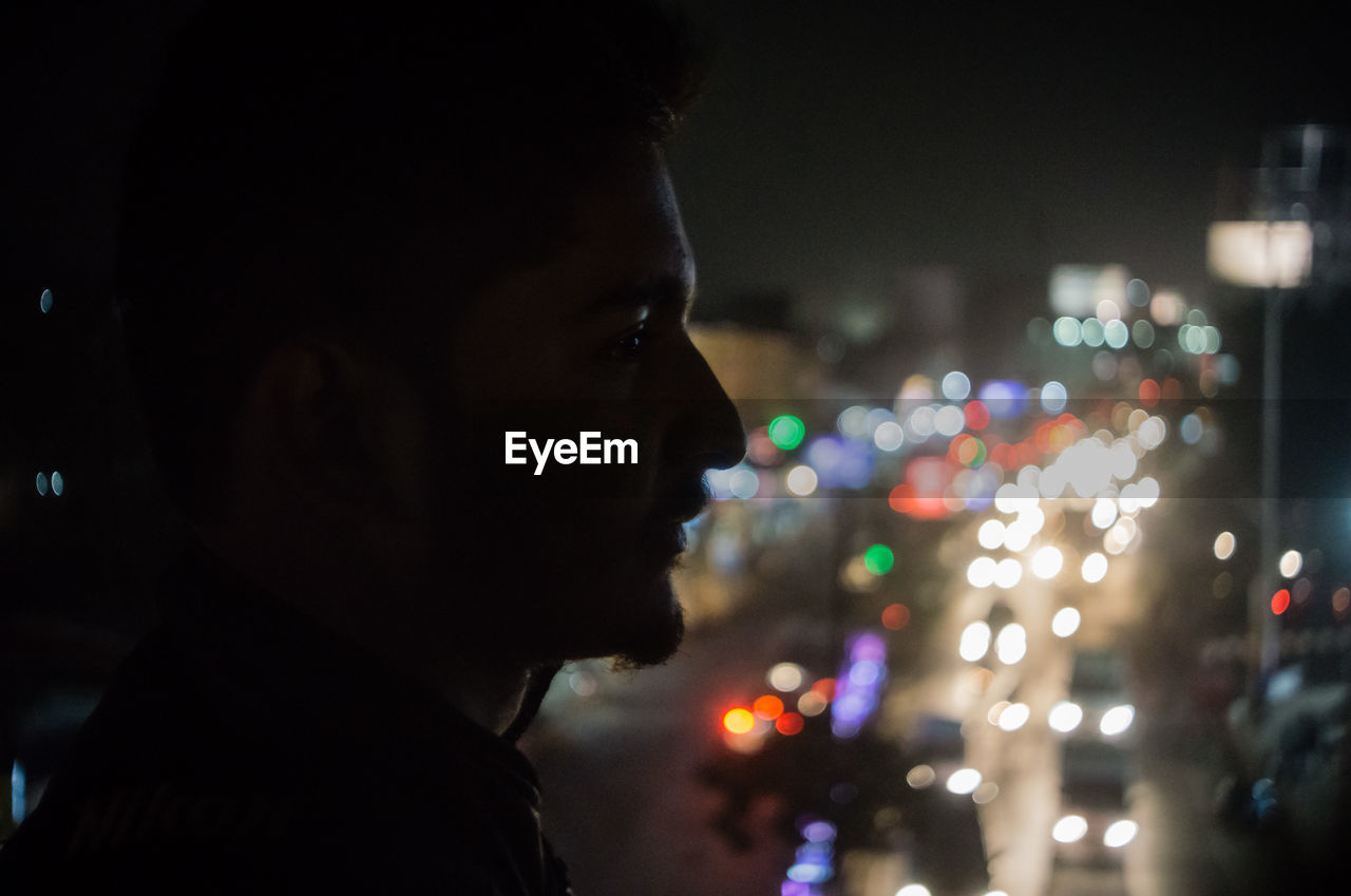 Close-up of man in illuminated city