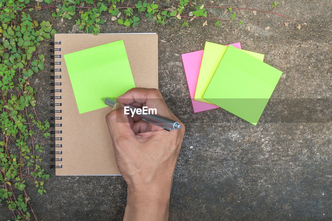 HIGH ANGLE VIEW OF HAND HOLDING PAPER