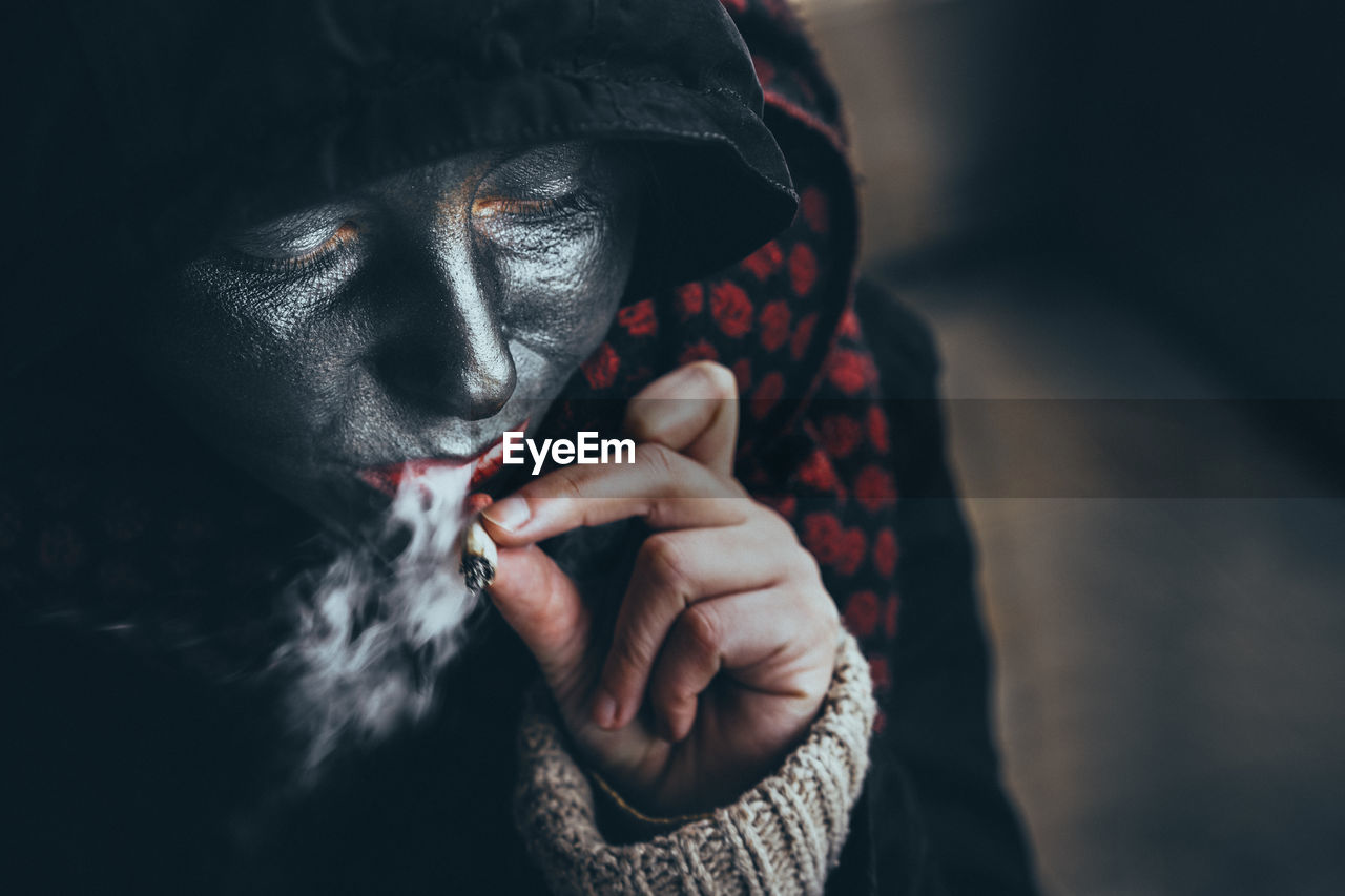 Close-up of woman with face paint smoking cigarette